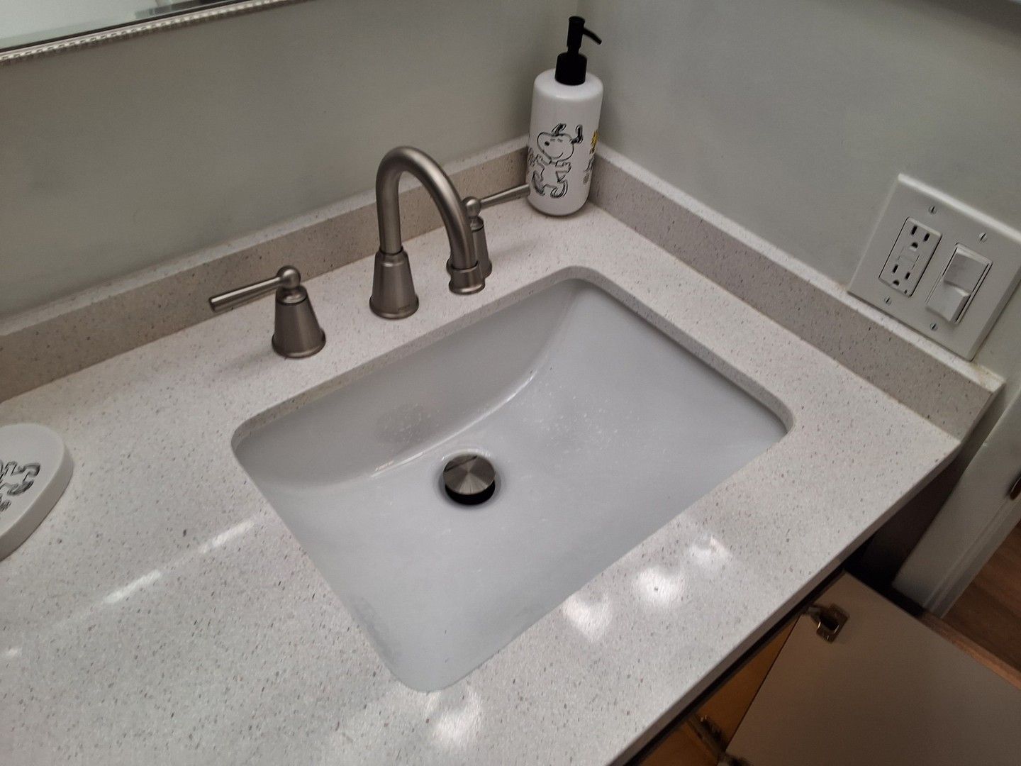Bathroom sink with chrome faucet, soap dispenser, and beige countertop corner
