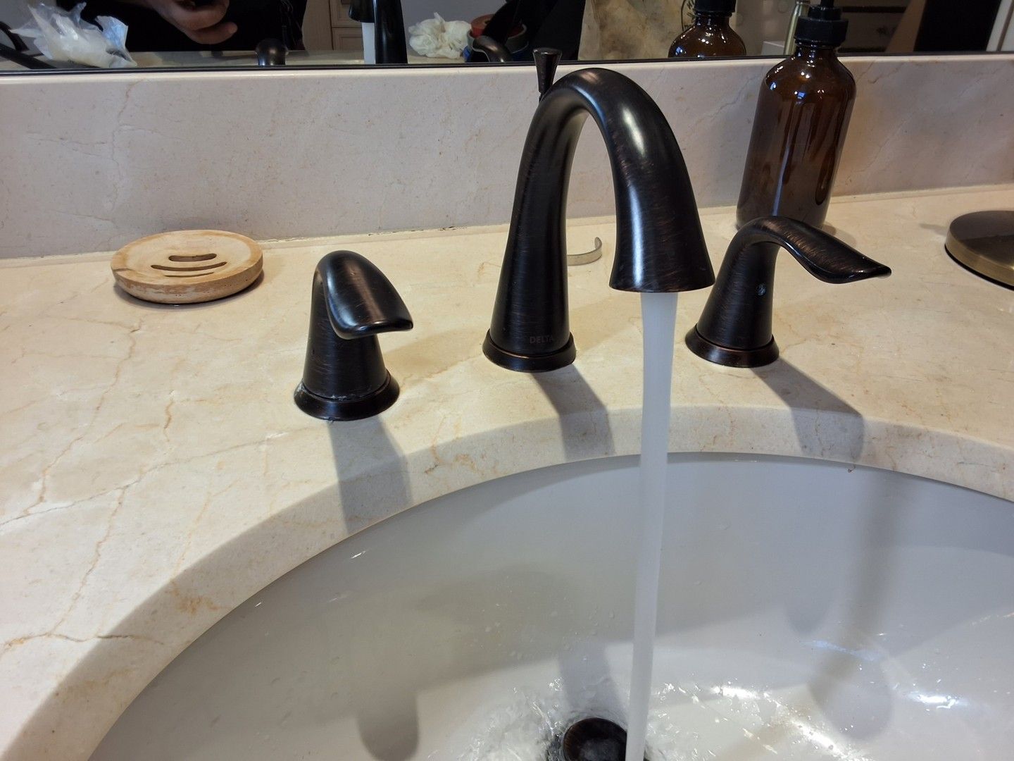 Bathroom sink with black faucet running water into a white basin