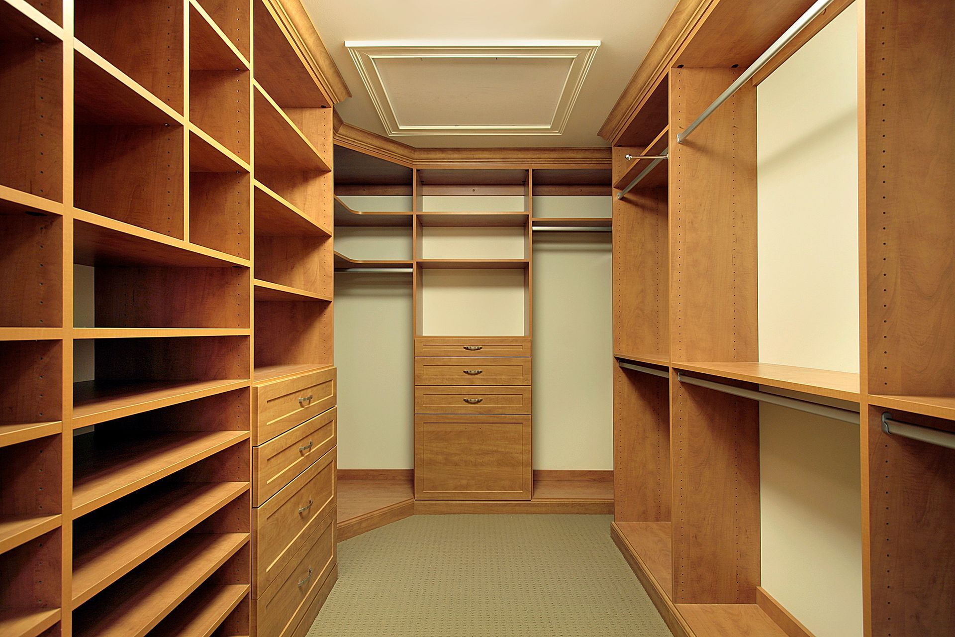 Walk-in closet with wooden shelves, drawers, and beige carpet, viewed from the doorway