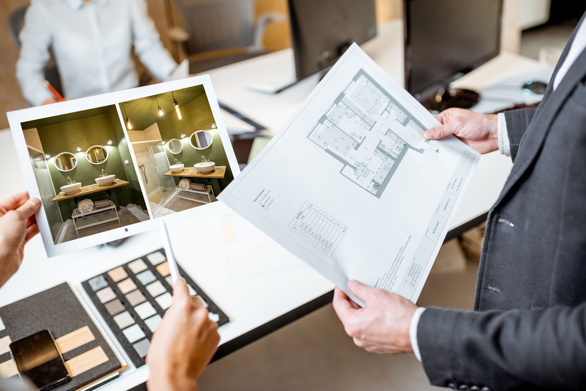 Hands reviewing a floor plan and interior design photos at a desk