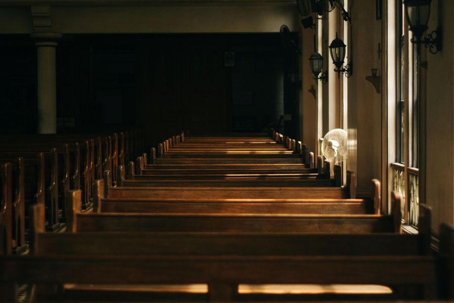 A row of wooden benches in an empty church.