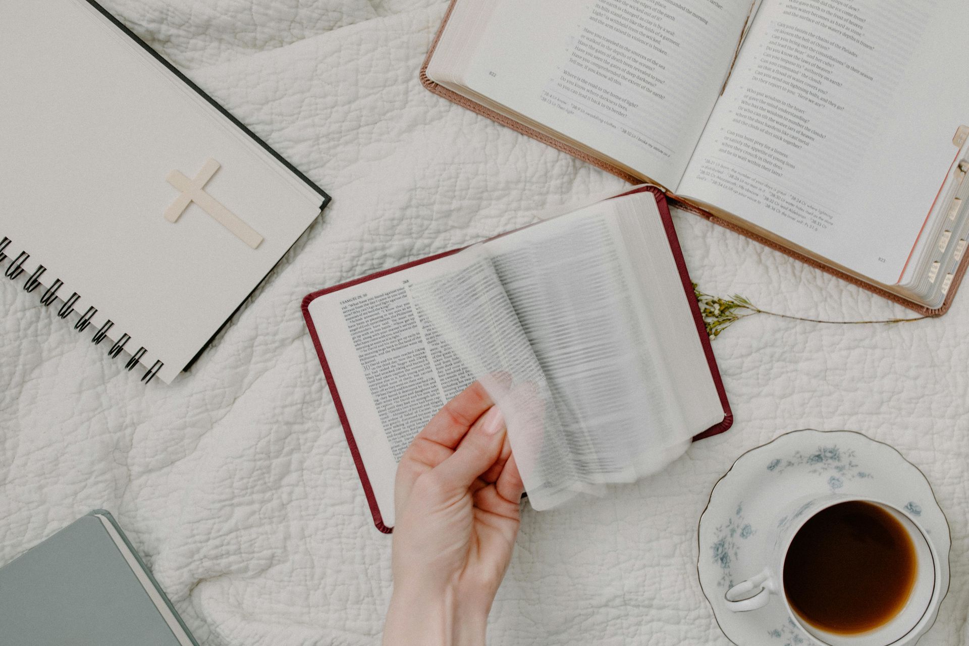A person is reading a book next to a cup of coffee.