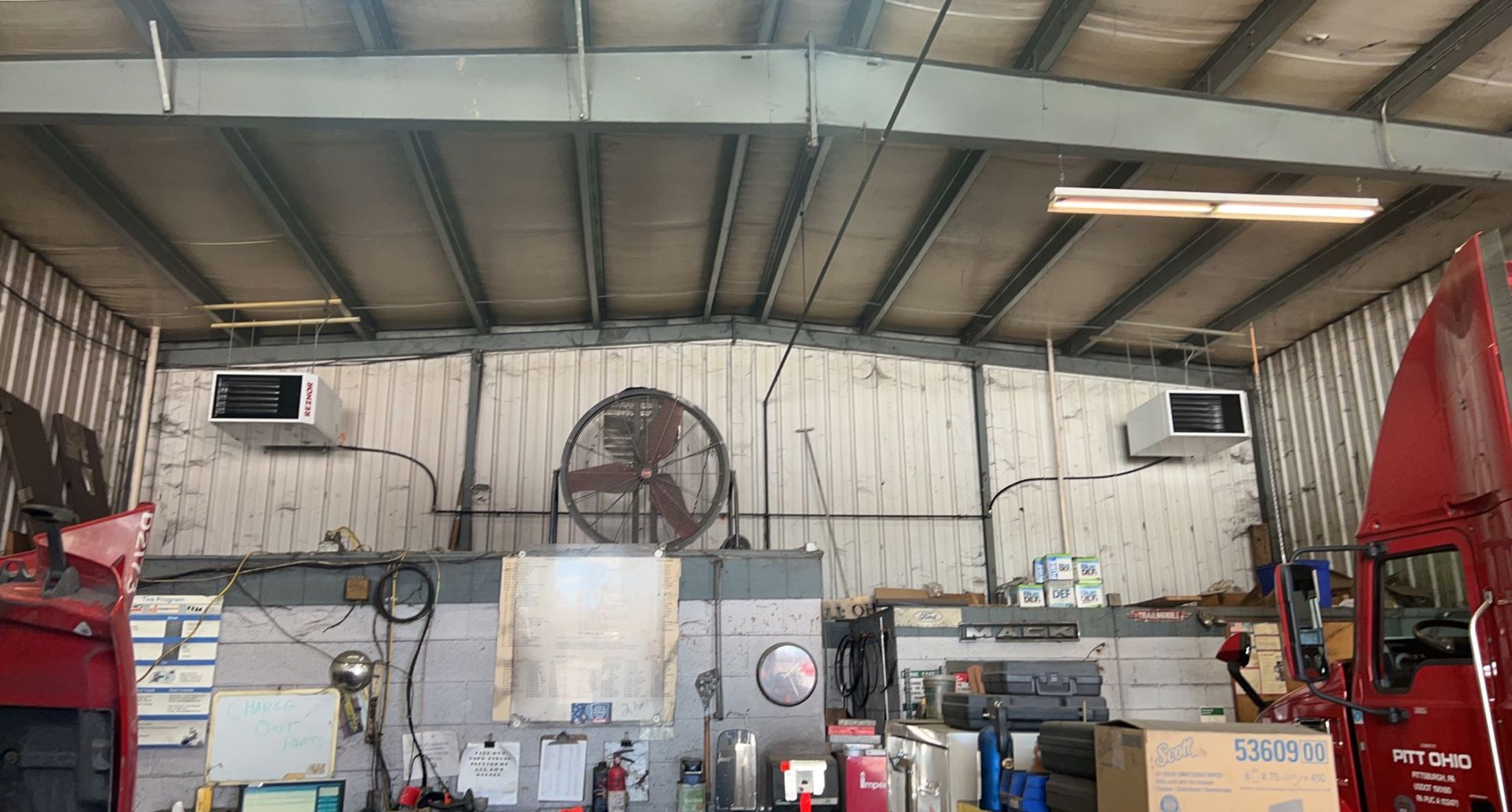 a red van is parked in a garage with a fan hanging from the ceiling .