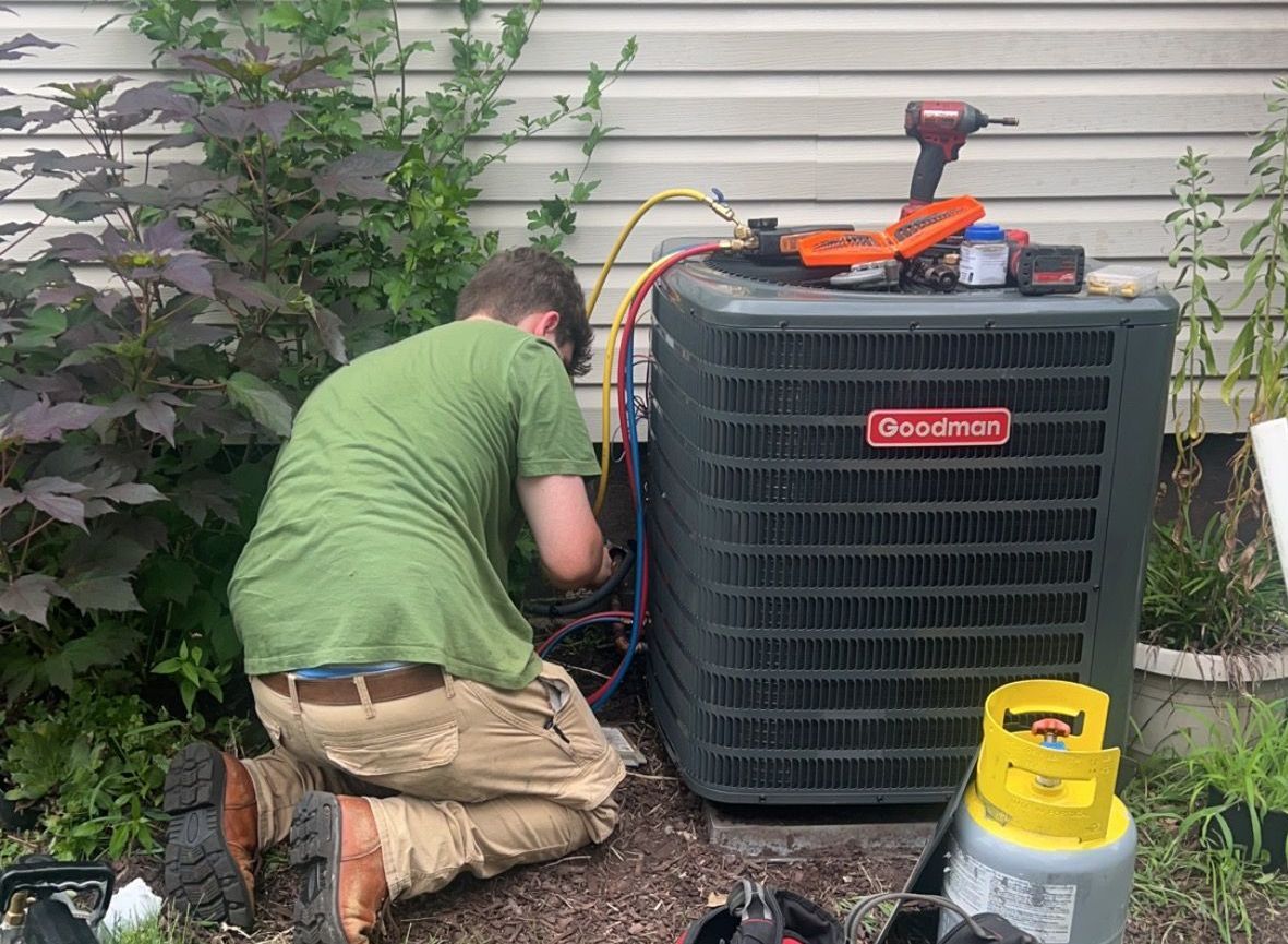 a man is kneeling down in front of an air conditioner .