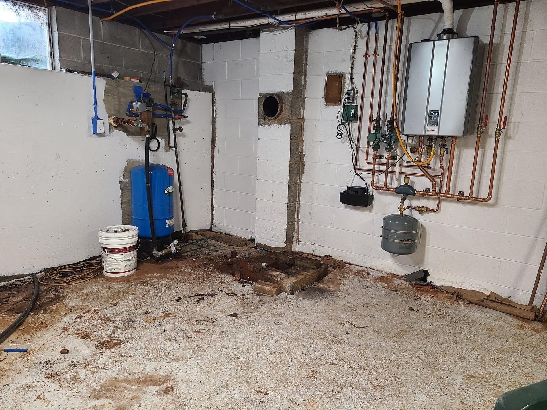 a basement with a heater and a bucket on the floor .