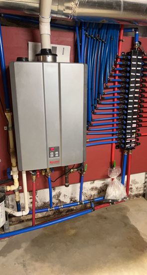 a water heater is sitting in a basement next to a red wall .