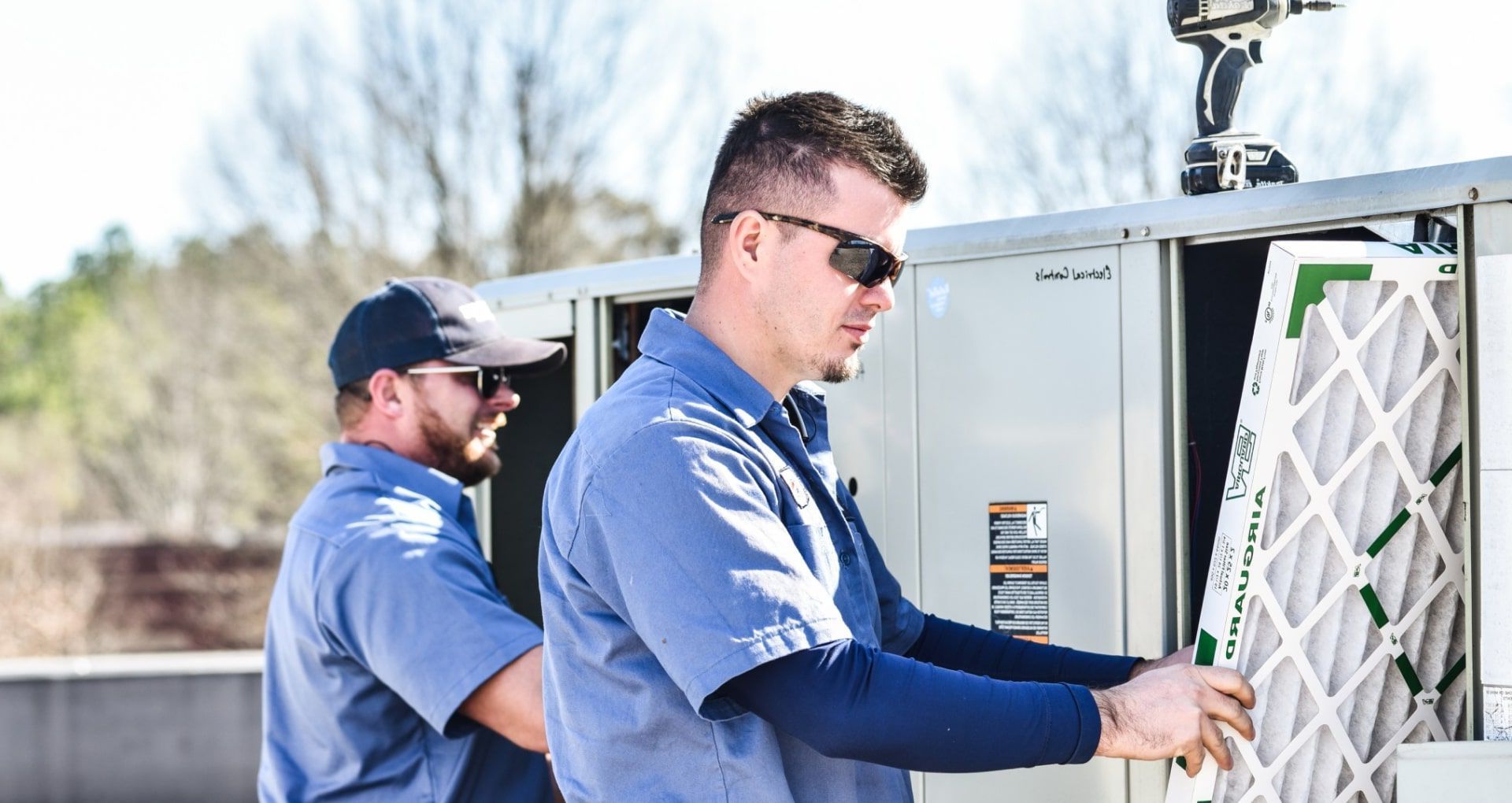 two men are working on an air conditioning system .