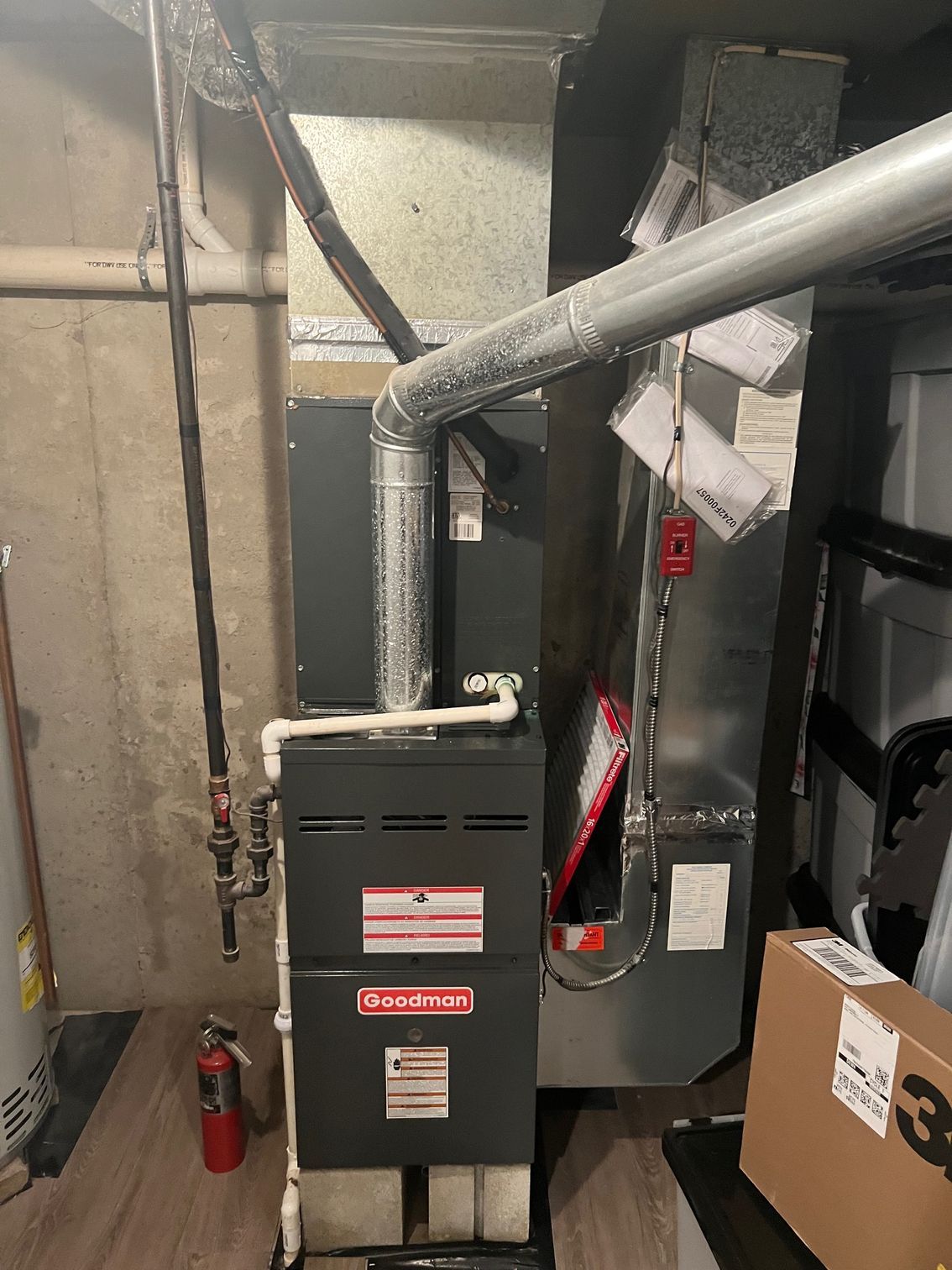 an air conditioner is sitting in a basement next to a fire extinguisher .