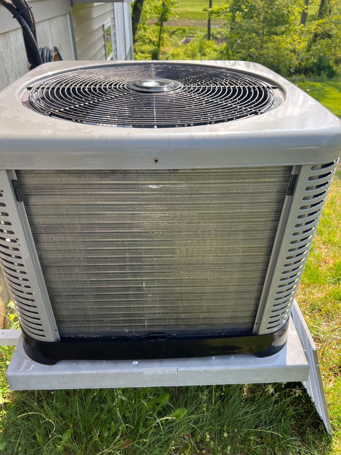 a large air conditioner is sitting on top of a metal stand in the grass .
