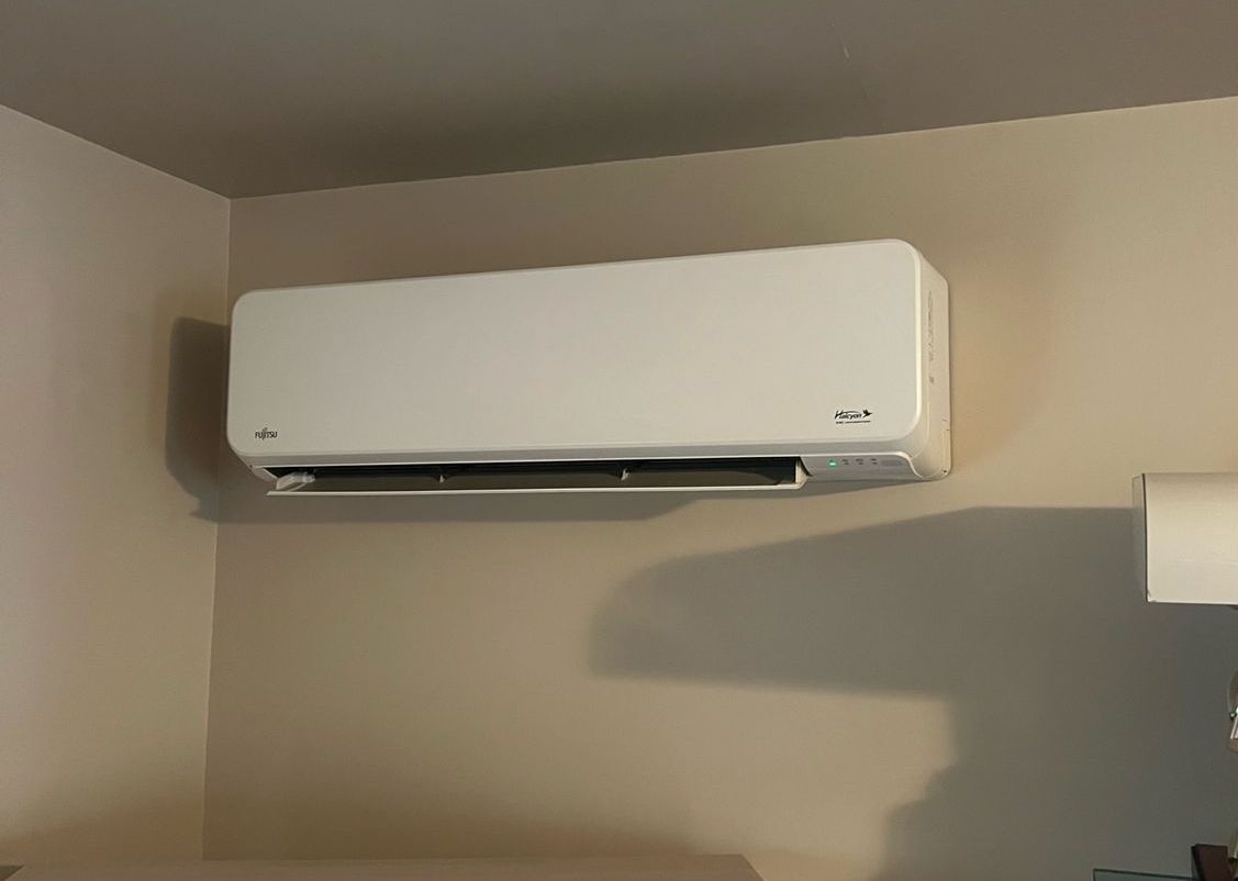 a white air conditioner is hanging on a wall in a room .