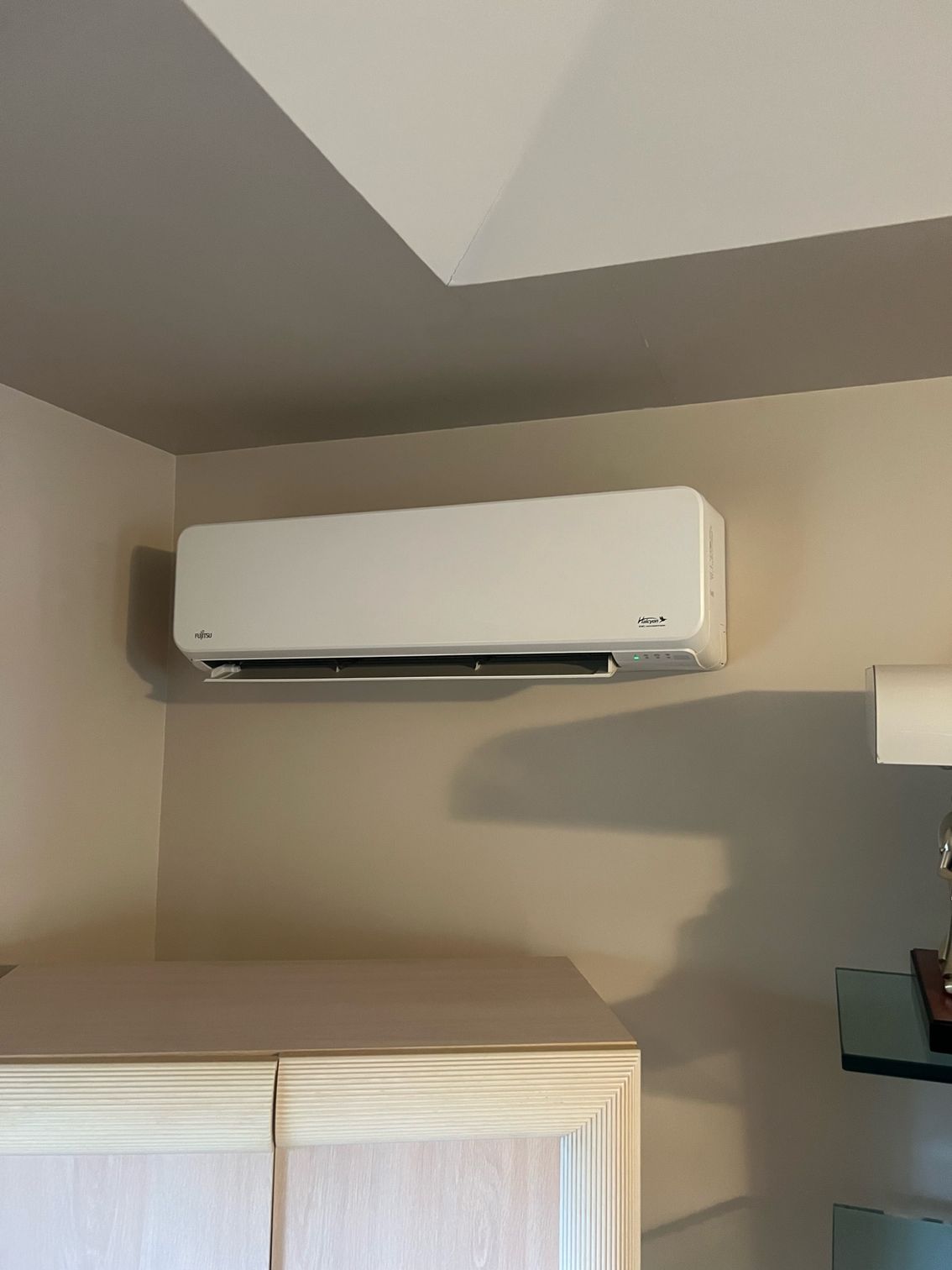 a white air conditioner is hanging on a wall in a room .