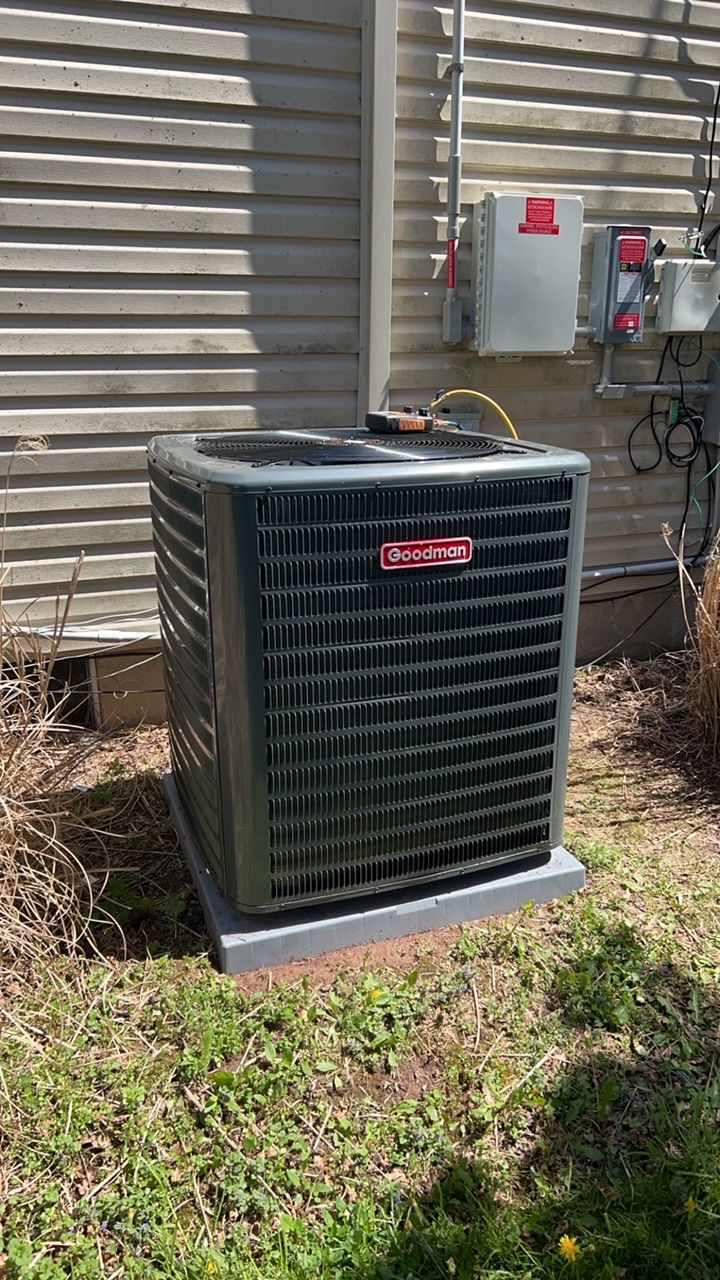 a large air conditioner is sitting in the grass next to a house .