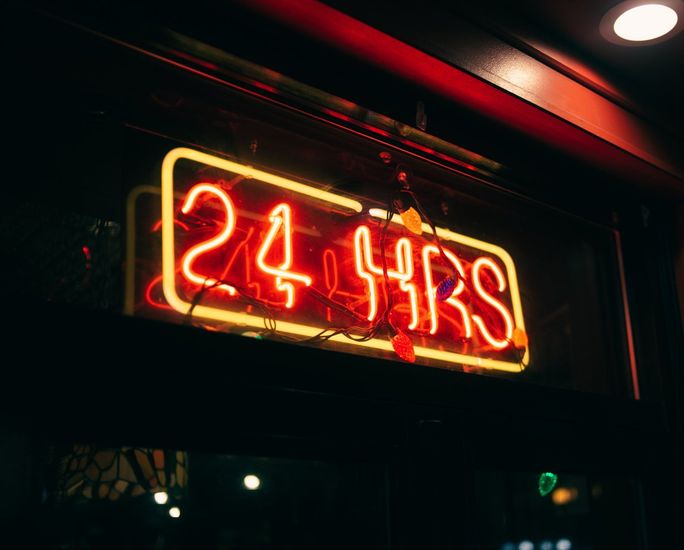 a neon sign that says 24 hrs is lit up at night