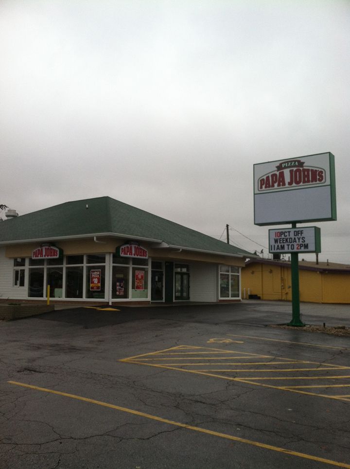 A papa john 's restaurant with a parking lot in front of it