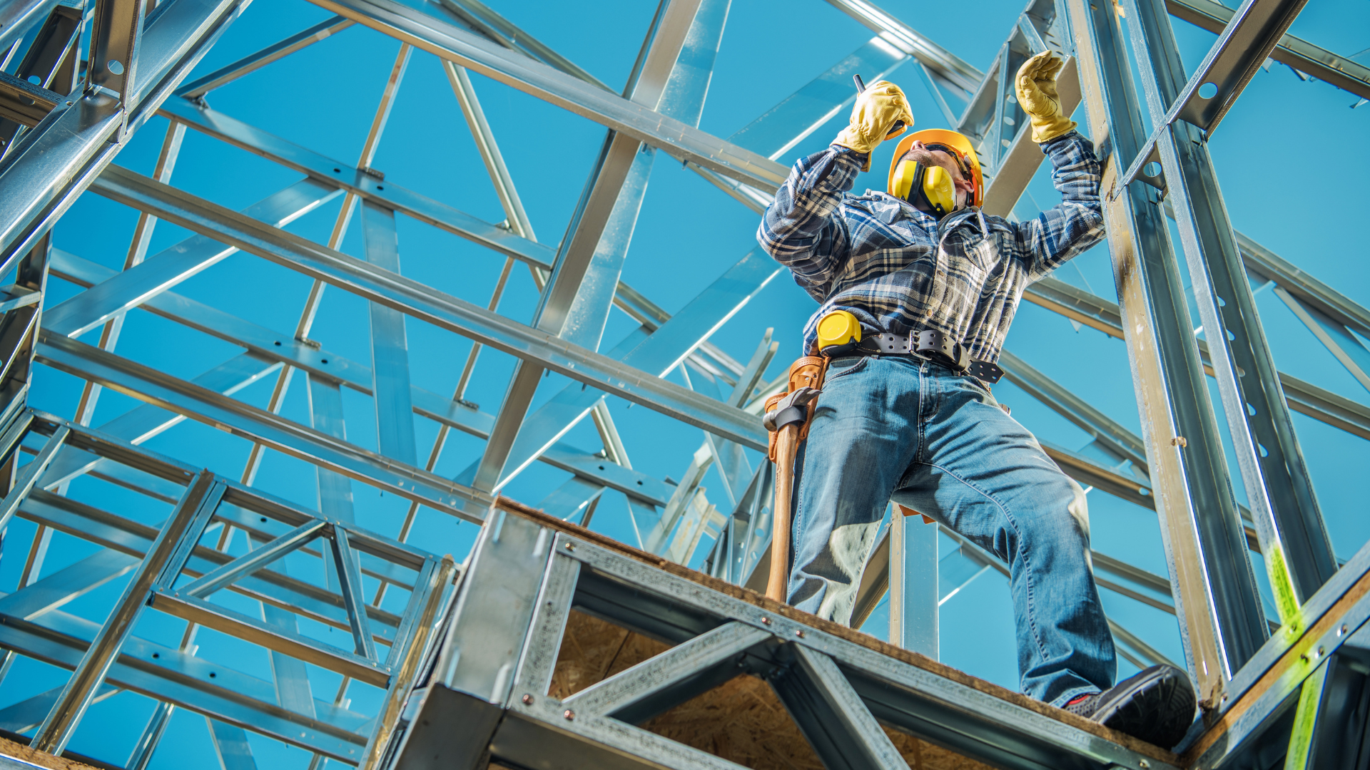 A construction worker is standing on top of a metal structure.