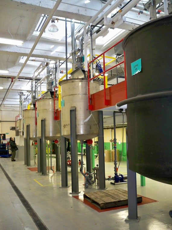 A row of large tanks are lined up in a factory