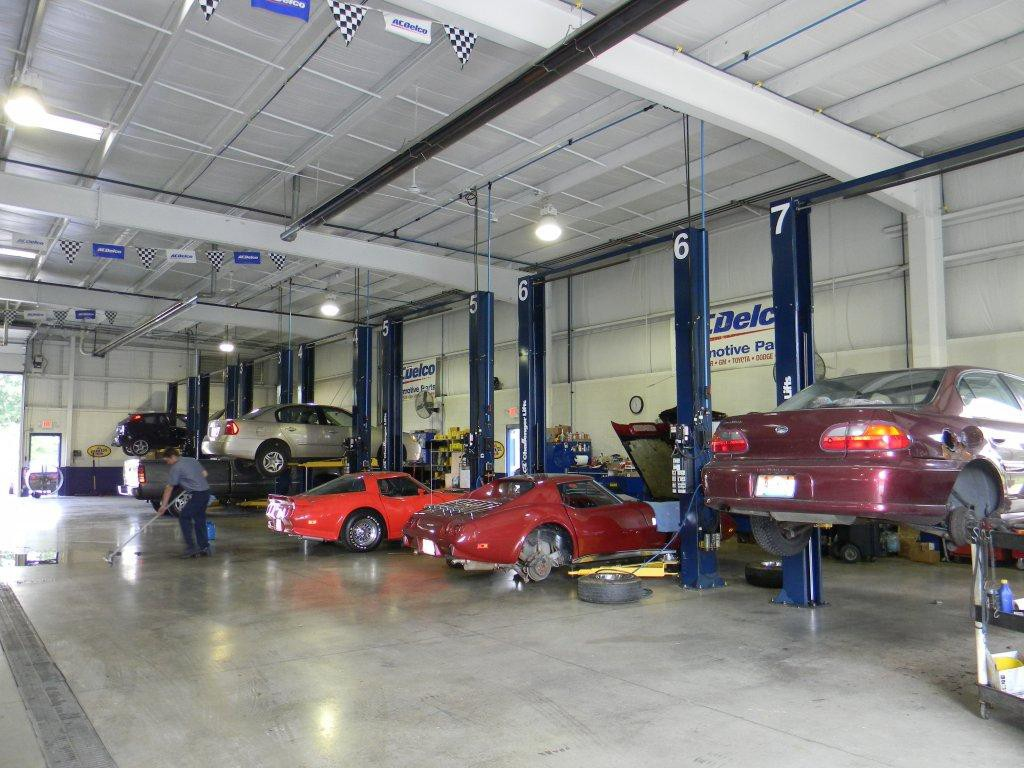 A row of cars are sitting on lifts in a garage.