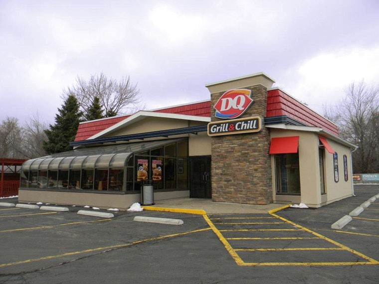 A dq grill and chill restaurant with a parking lot in front of it