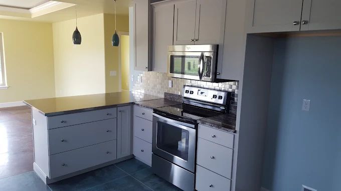 Kitchen with gray cabinets, stainless steel appliances, and an island with dark countertop.