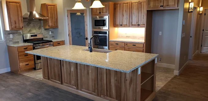 Kitchen with wooden cabinets, granite countertops, and an island with a sink.