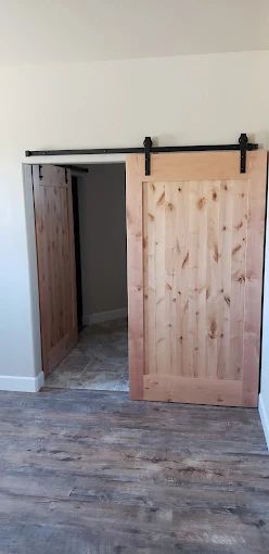 Sliding barn doors with wooden texture, in a room with wood-like flooring.