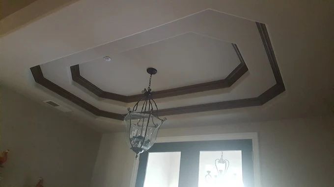 Octagon-shaped ceiling detail with wood trim and hanging chandelier; interior.