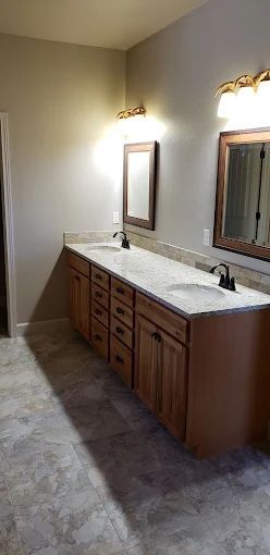 Bathroom with a long vanity, two sinks, mirrors, and two light fixtures.