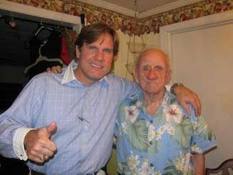 Two men are posing for a picture and one of them is giving a thumbs up.