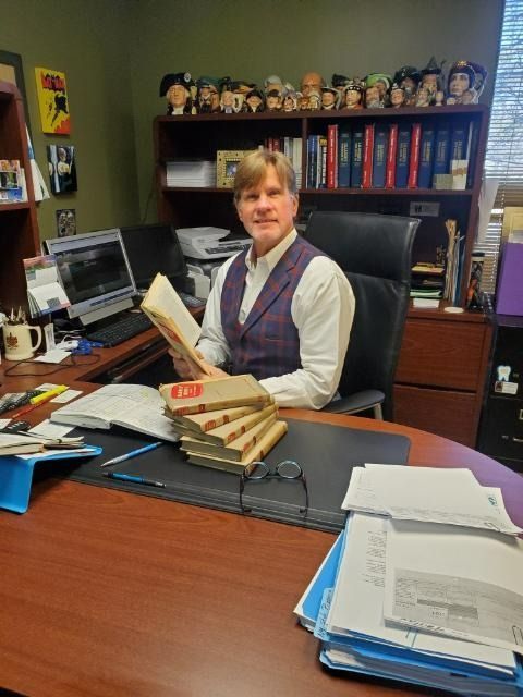 A man is sitting at a desk reading a book