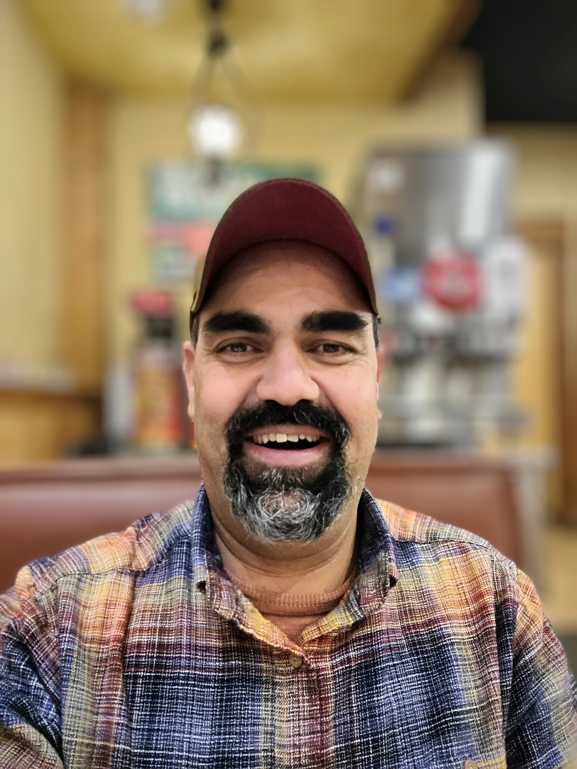 A man with a beard and a hat is smiling for the camera.