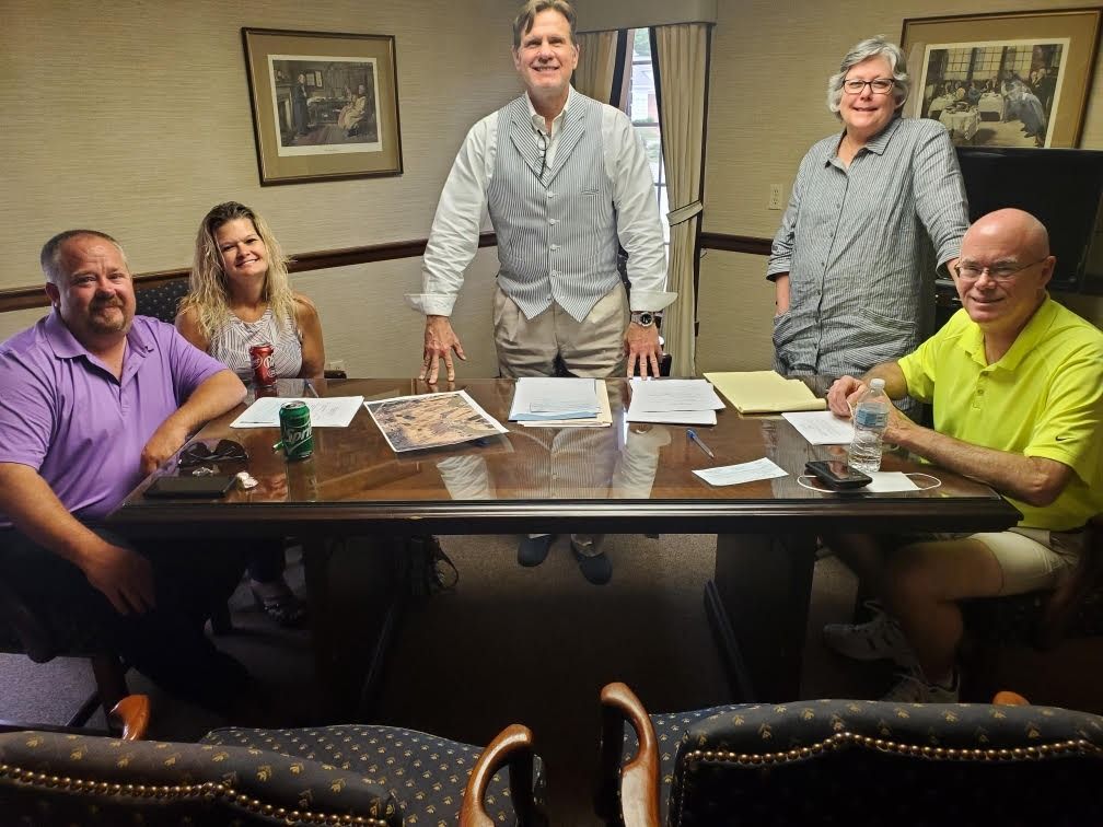 A group of people are sitting around a table in a conference room.