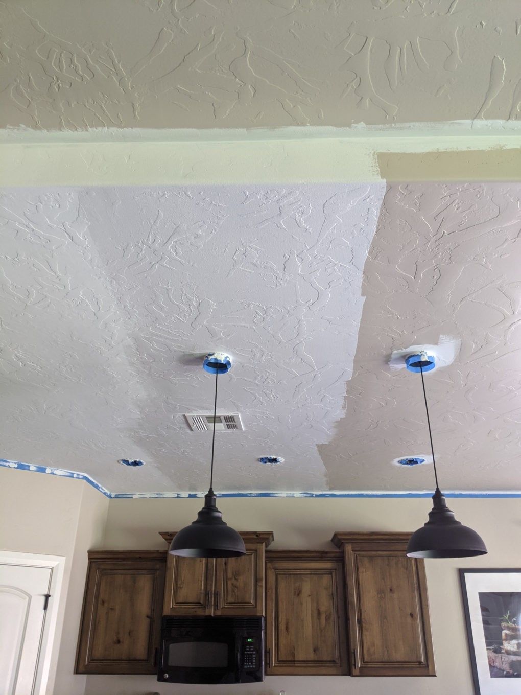 A painter using an airless painting sprayer to cover the ceiling surface with white paint.