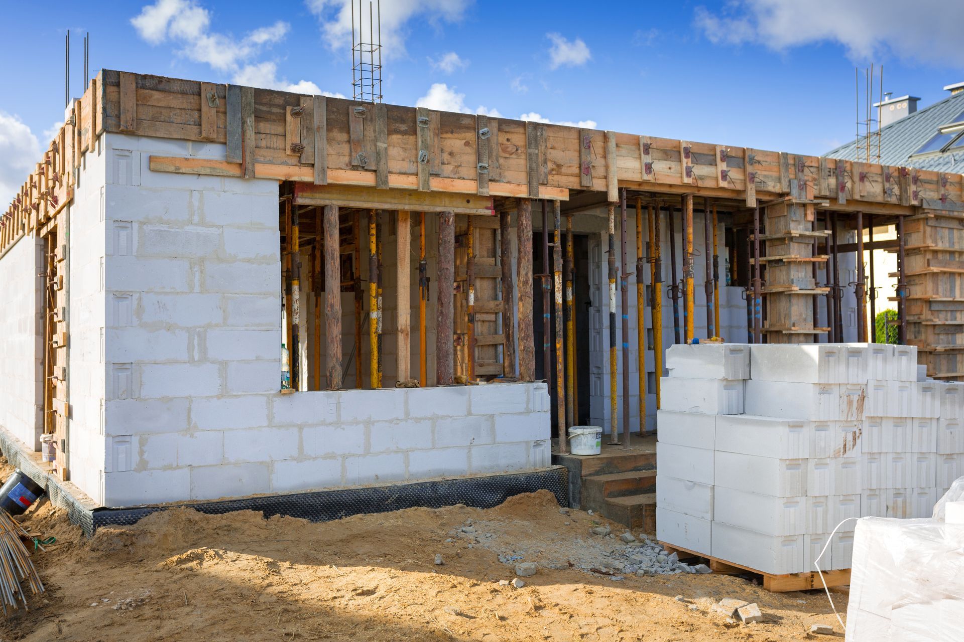 Construction site with cranes atop a partially built building against a blue sky.