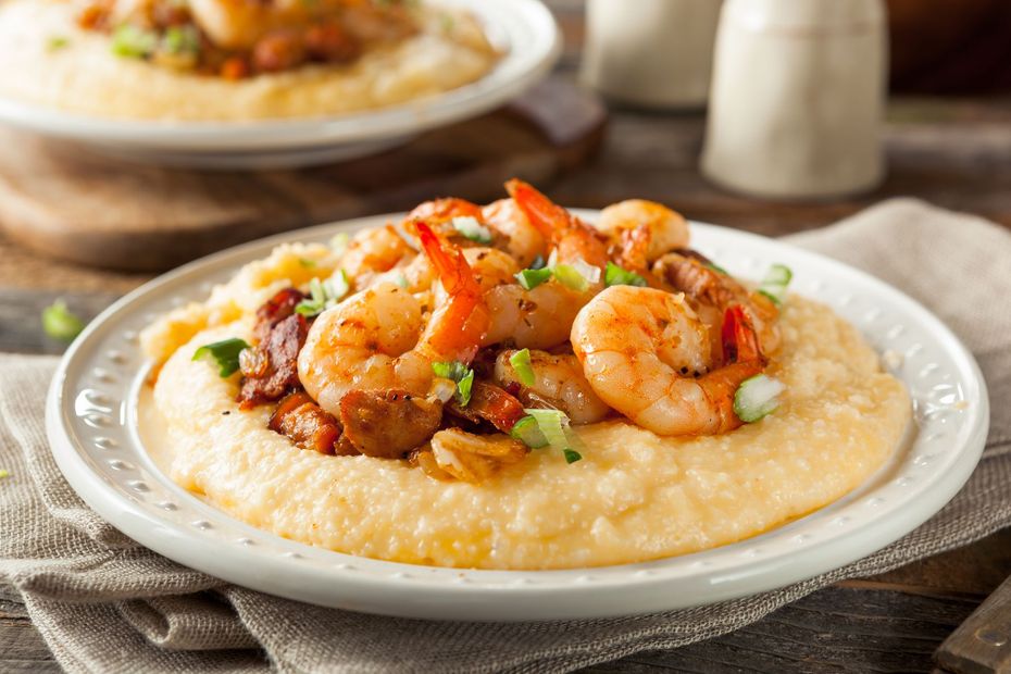 A close up of a plate of shrimp and grits on a table.
