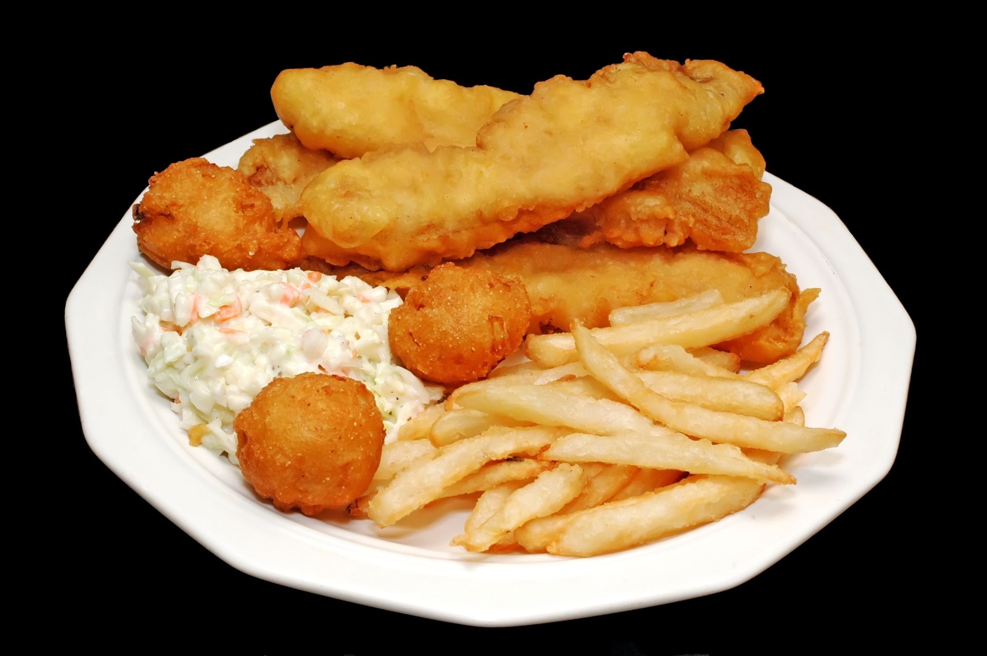 A white plate topped with fried fish french fries and coleslaw