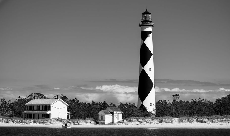 A black and white photo of a lighthouse on a small island