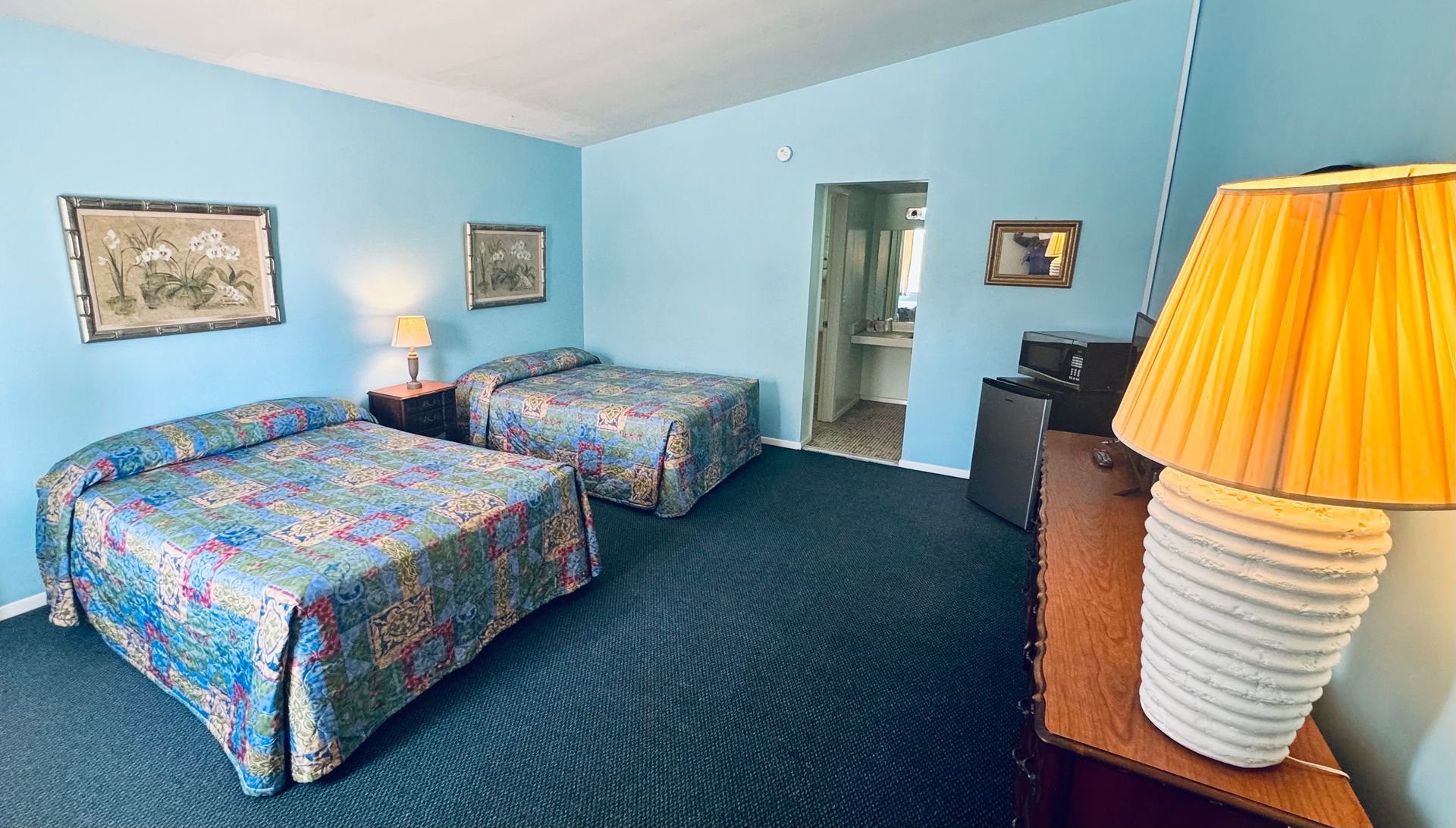A hotel room with two beds and a lamp