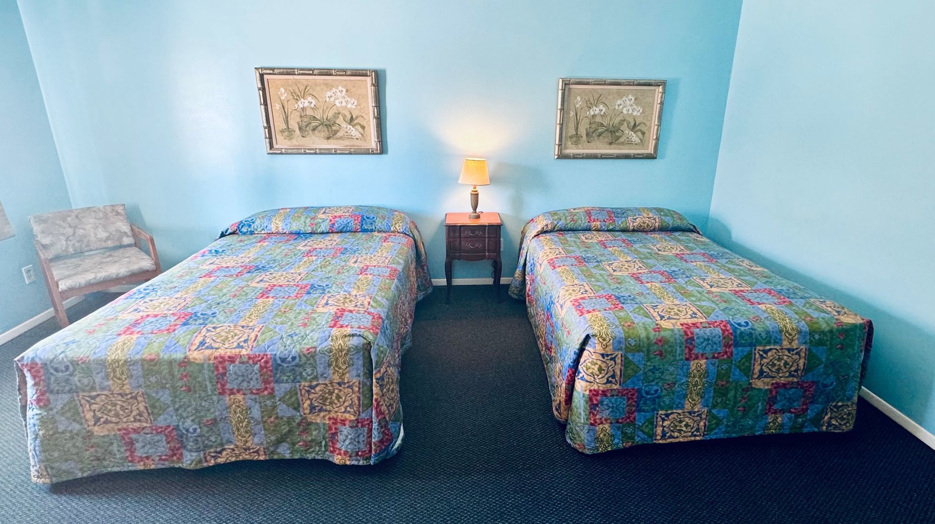 A hotel room with two beds and two lamps.