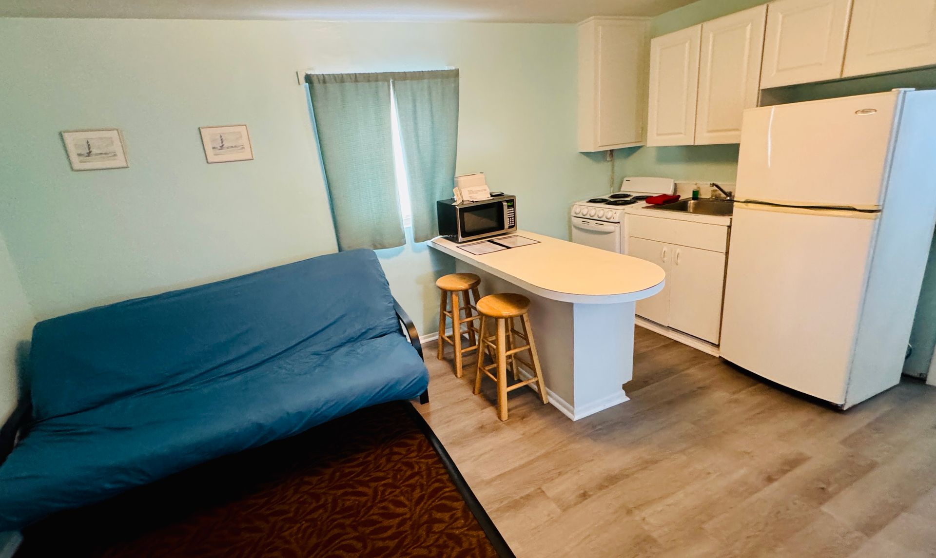 A small kitchen with a blue futon and a white refrigerator.