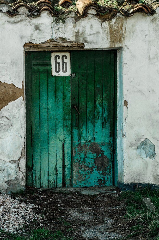 An einer weißen Wand befindet sich eine grüne Tür mit der Nummer 66.