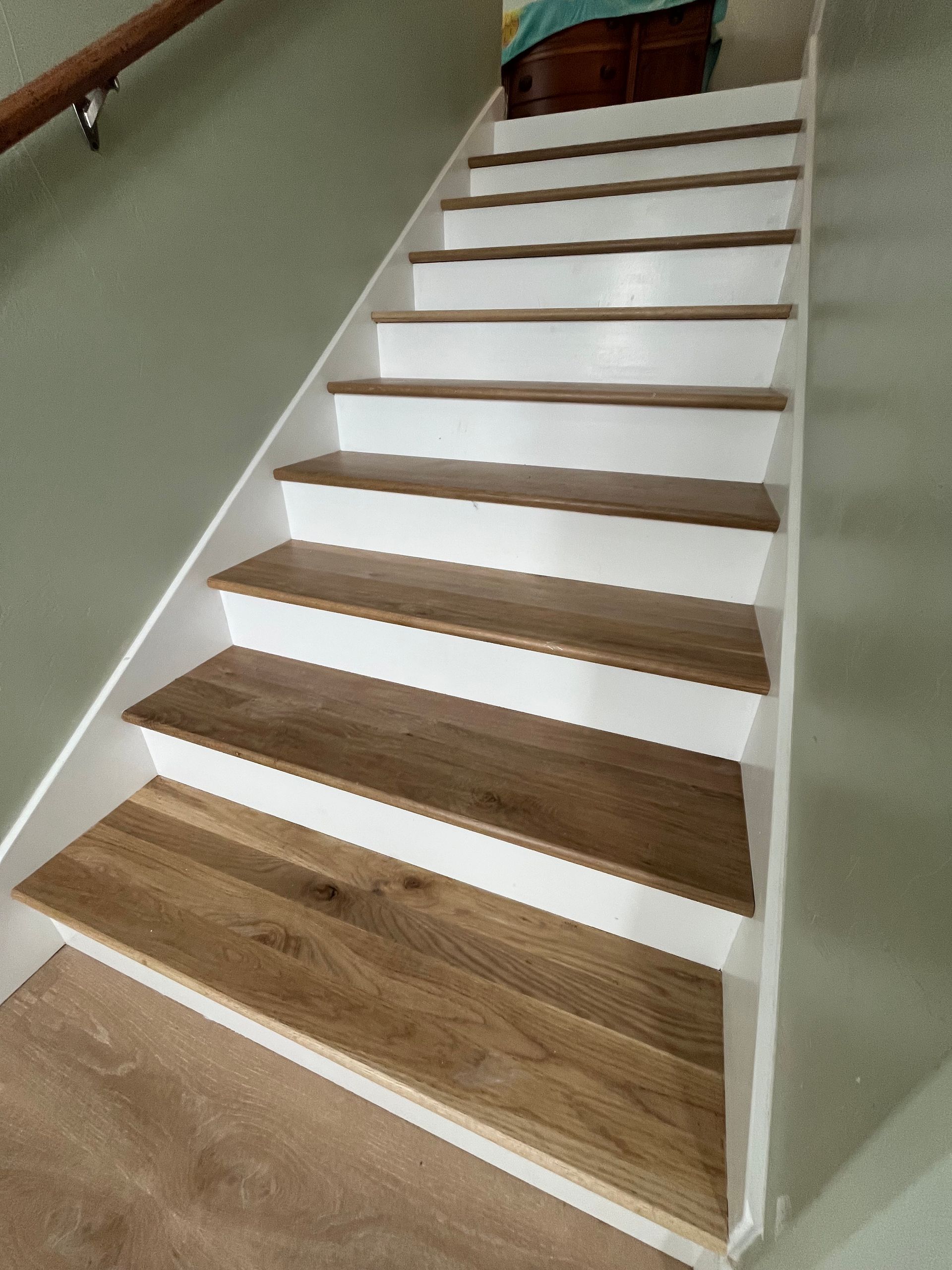 Staircase with light oak wood treads and crisp white risers, viewed from the bottom looking up toward a landing.