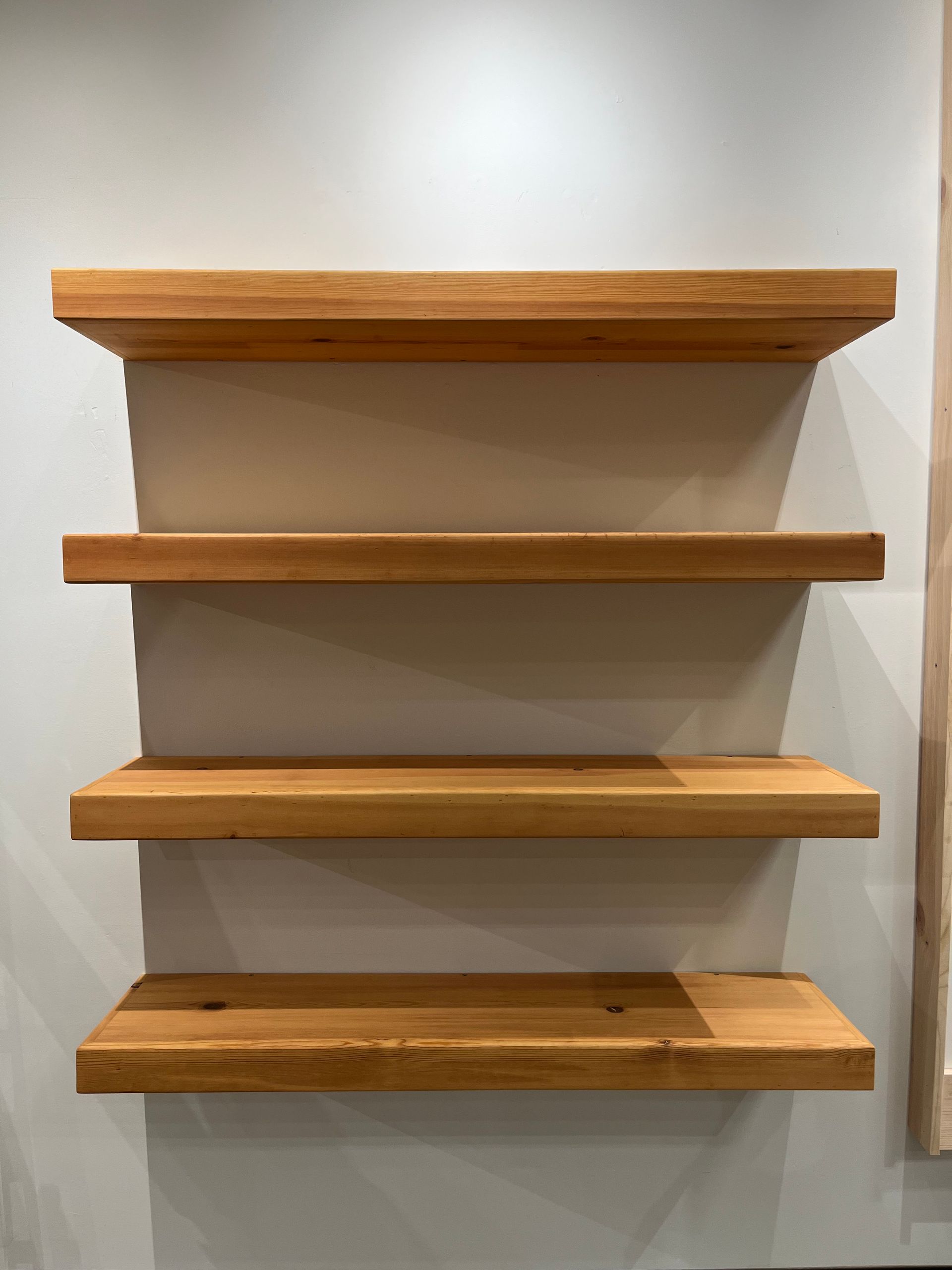 Four wooden floating shelves mounted on a light-colored wall.