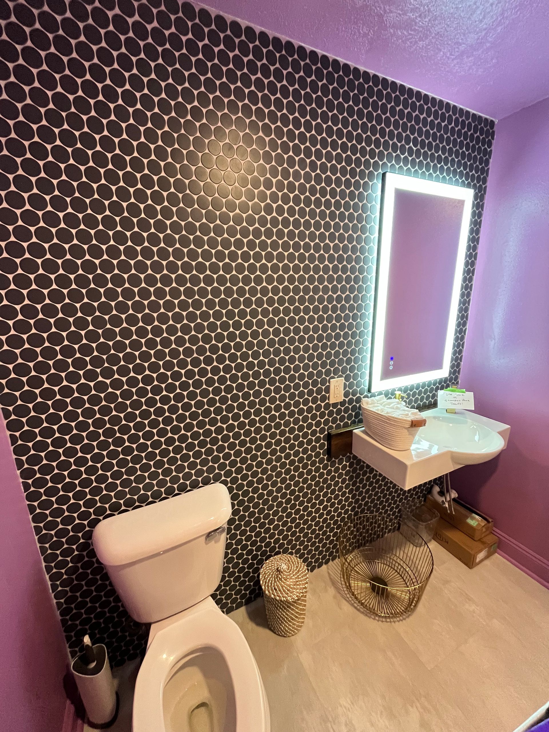 A modern bathroom features a purple-walled space with a black and white geometric honeycomb-tiled accent wall.