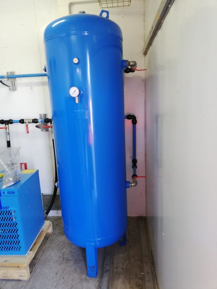 Un grande serbatoio blu è posizionato in una stanza accanto a una macchina.