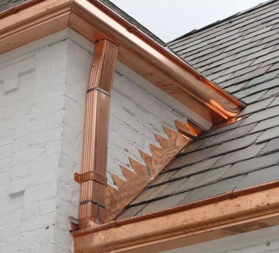 A copper gutter installed along the edge of a house, showcasing its rich metallic sheen and intricate design.