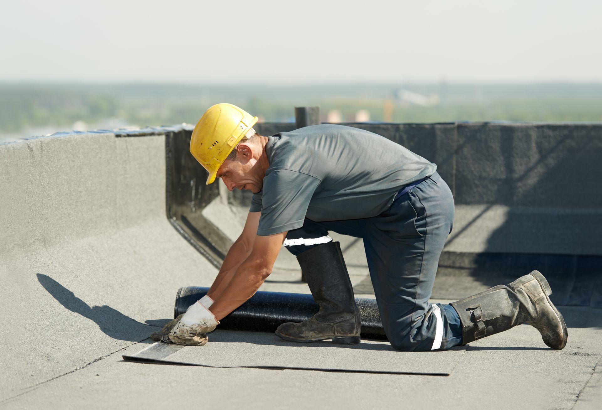 A worker applying roofing felt on a flat roof surface, ensuring proper insulation and waterproofing.
