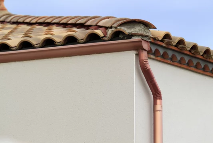 An elegant copper gutter installed along the edge of a house, gracefully channeling rainwater away from the roof and down into a drain.