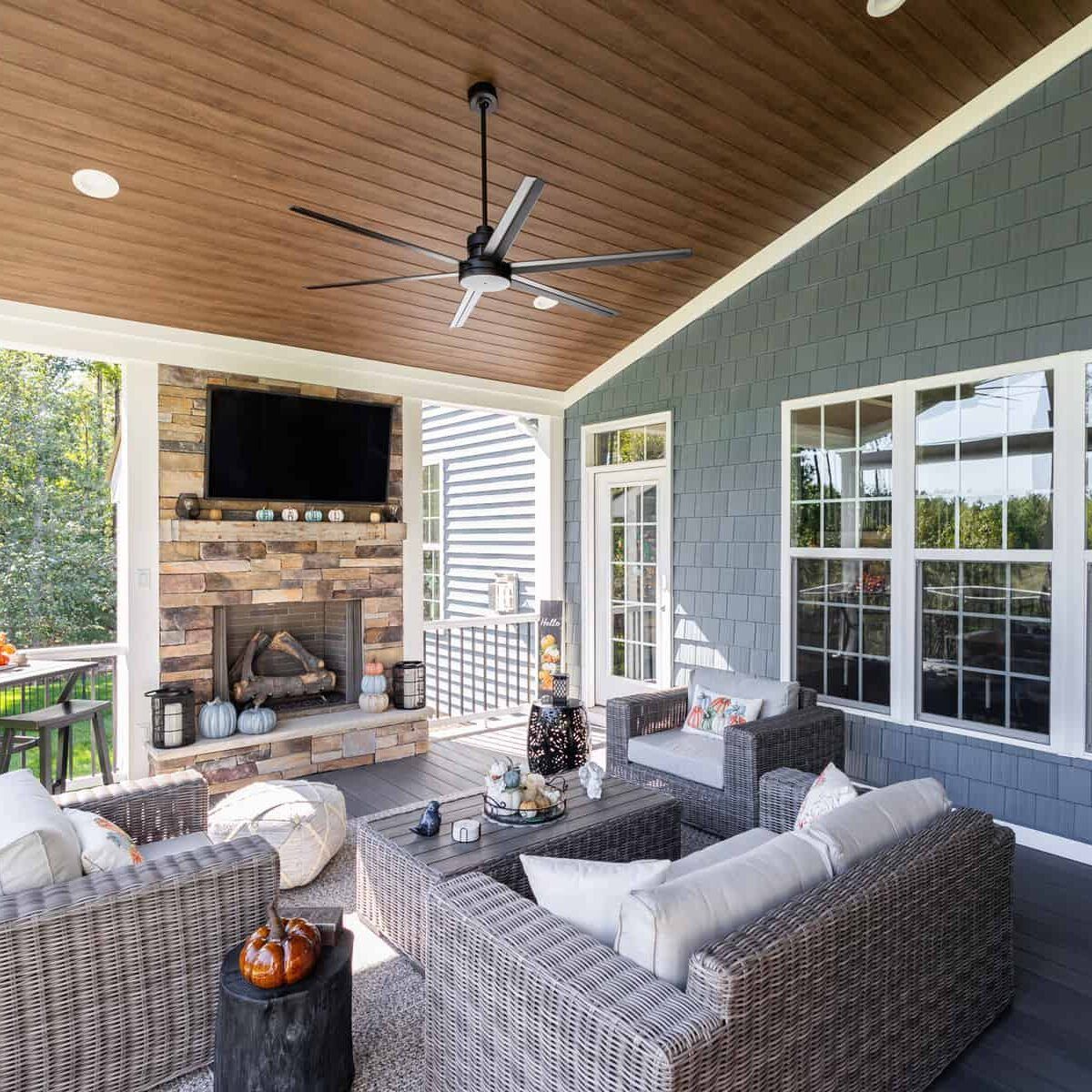 Covered patio with fireplace, seating, ceiling fan, and blue siding.