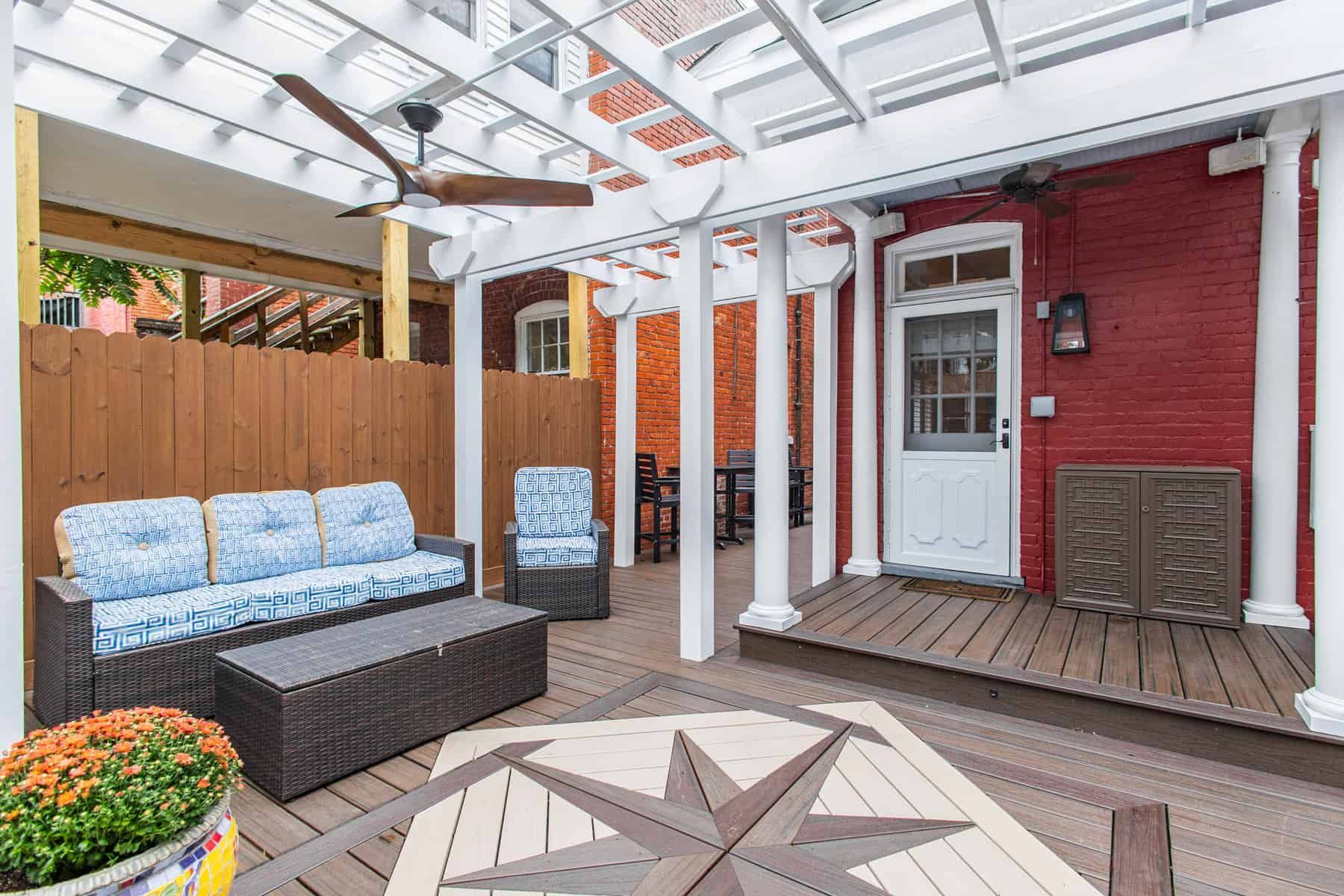 Outdoor patio with a seating area, brick wall, pergola, and wooden deck.