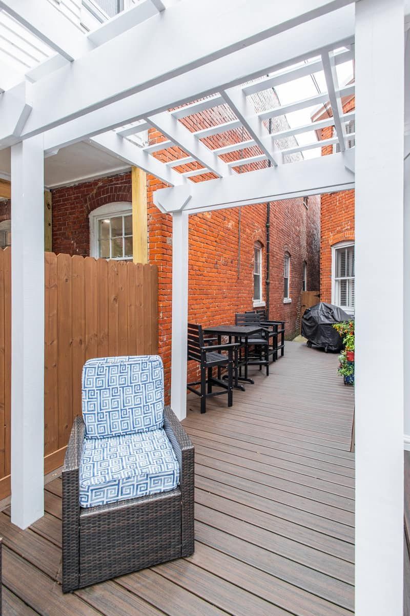 Outdoor patio with pergola, brick walls, a chair, and tables.